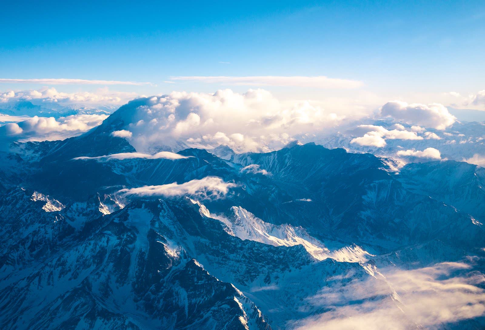 Vista aérea de las cumbres nevadas de los Andes asomando entre las nubes