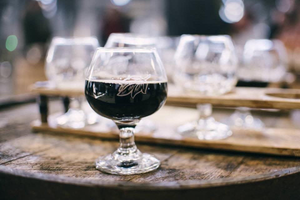 Copa de vino tinto sobre un barril de madera, lista para la degustación